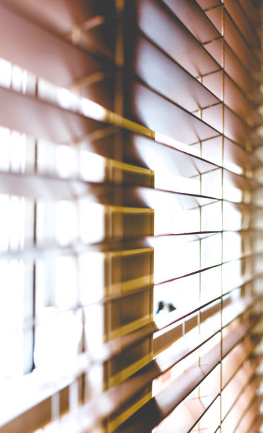 istock Wooden window blinds partially closed with bright light going through 867346778