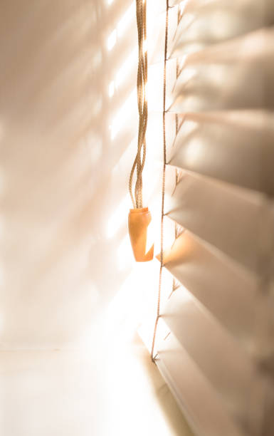 istock Wooden window blinds partially closed with bright light going through 867348002