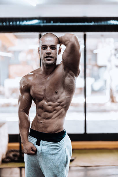 istock Young man showing his muscles in the gym 867352608