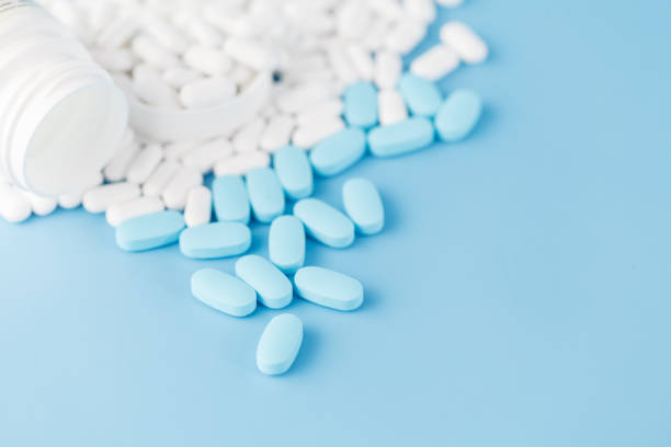 istock White pills on blue background. Closeup view 867363812