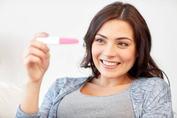 istock happy woman looking at home pregnancy test 867369618
