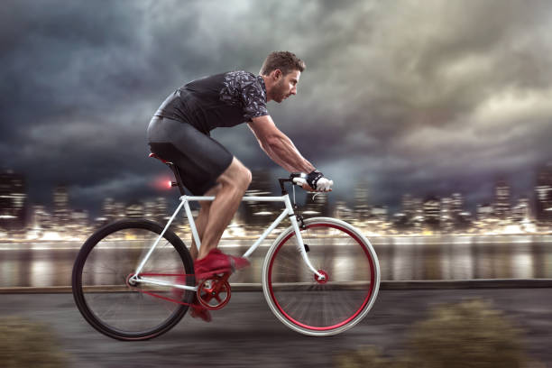 Cyclist cycling in front of a nightly skyline
