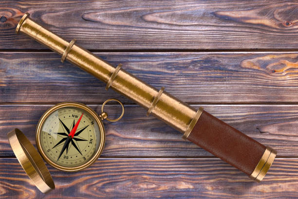istock Golden Vintage Telescope Spyglass with Compass over Wooden Table. 3d Rendering 867383734