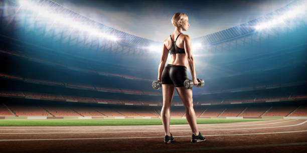 istock female athlete with dumbbells on stadium 867390704
