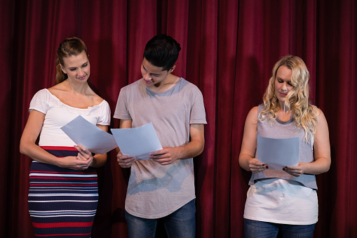 Actors reading their scripts on stage in theatre