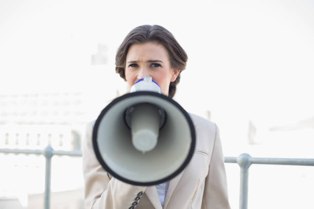 istock Frowning stylish brown haired businesswoman using a megaphone 867395906