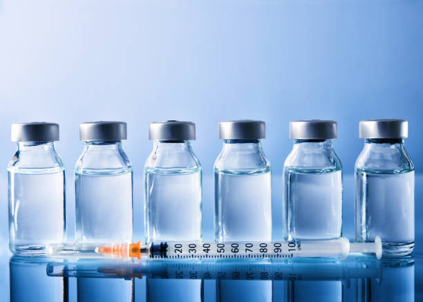 istock Row of vials and syringe on blue table front view 867398372