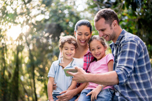 istock Happy family social networking outdoors using a cell phone 867401900