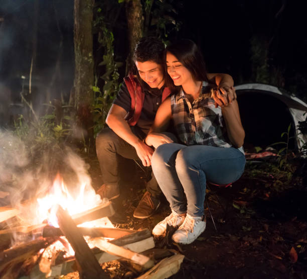 istock Young couple camping and looking happy by the bonfire 867402088