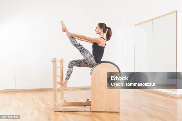 Beautiful Woman Performing Pilates Exercise Training On Barrel Equipment Stock Photo - Download Image Now