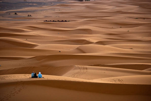 um casal de turistas ocidentais, acompanhados de guia de berber, esperando o nascer do sol de manhã - travel adventure water oman - fotografias e filmes do acervo