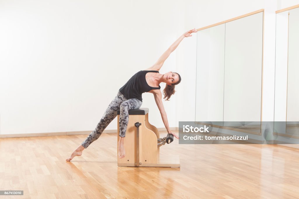 Pilates lesson on barrel, personal trainer coaching young beautiful woman Pilates Stock Photo