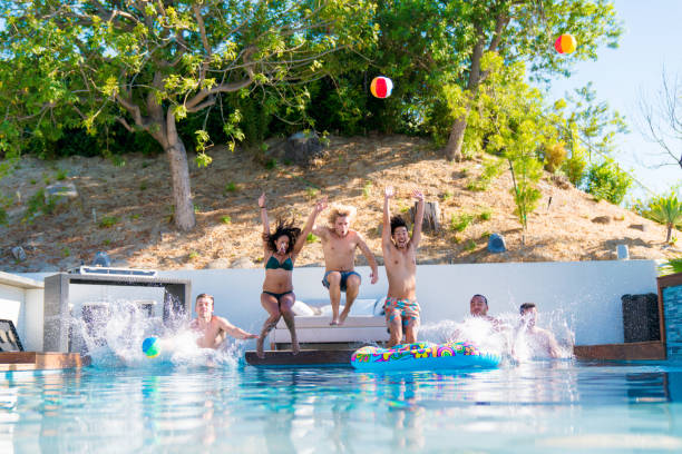 istock Group of friends jumping into a swimming pool together 867413290