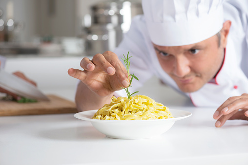 Chef is preparing pasta plate for service