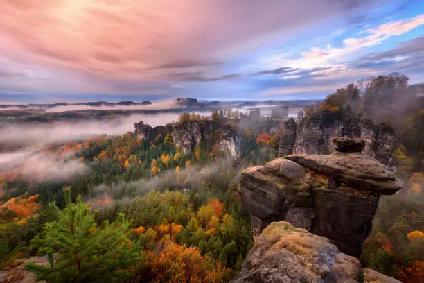 Foggy sunrise in the Saxon Switzerland, Germany, view from the Bastei lookout point. The Bastei is a tourist attraction for over 200 years.