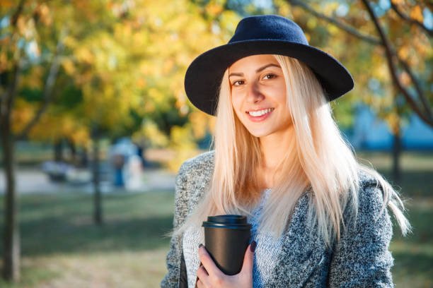 istock Young girl in a hat posing against a tree in a park. 867473184