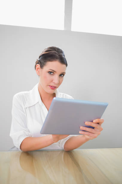 istock Serious pretty businesswoman working on tablet pc 867483912