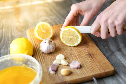 Alternative medicine with lemon, garlic and honey over rustic background.  Woman prepare healthy treatment
