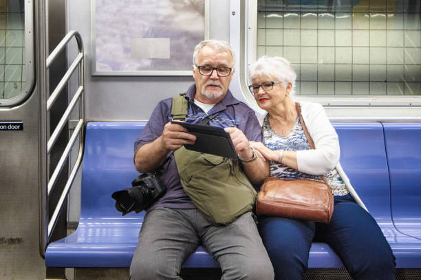 Senior couple look at information on tablet while in transit in subway