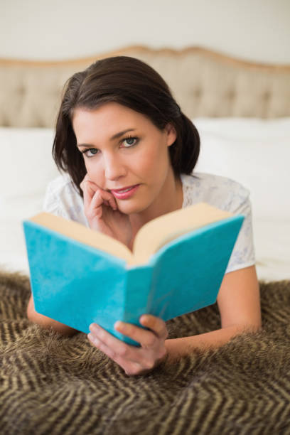 istock Pensive pretty brown haired woman reading a book 867491528