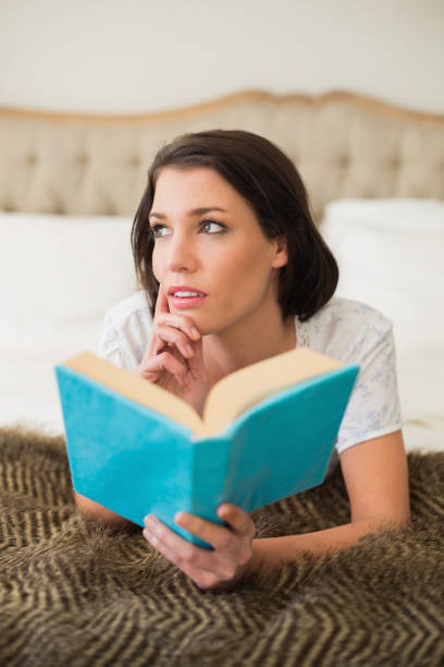 istock Thoughtful pretty brown haired woman holding a book 867491534