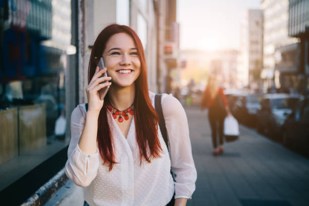 Lifestyle Young woman with coffee to go standing at the street and talking on mobile phone 3686 stock pictures, royalty-free photos & images