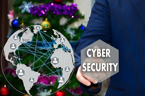 The businessman chooses CYBER SECURITY on the touch screen, the backdrop of the Christmas tree and decorations. Special toning .