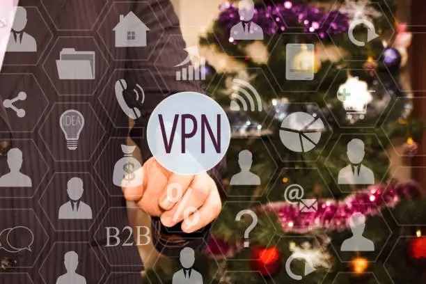 Photo of The businessman chooses a VPN on the touch screen, the backdrop of the Christmas tree and decorations