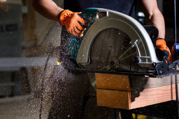 close-up of carpenter using electric circular saw to cut wood planks - sawdust imagens e fotografias de stock