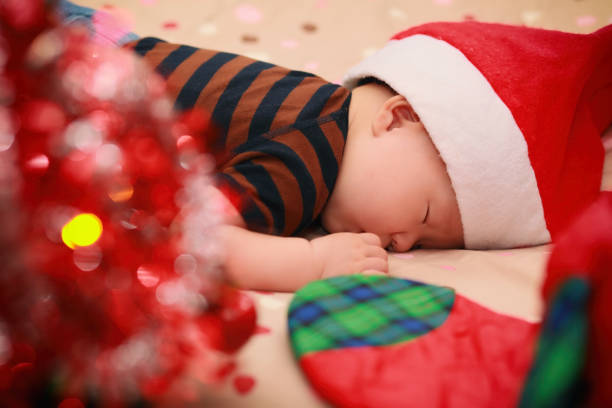bambino addormentato che indossa il cappello di babbo natale - baby santa claus christmas sleeping foto e immagini stock