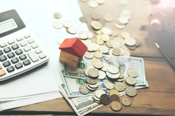money,calculator,piggy bank with house model on table