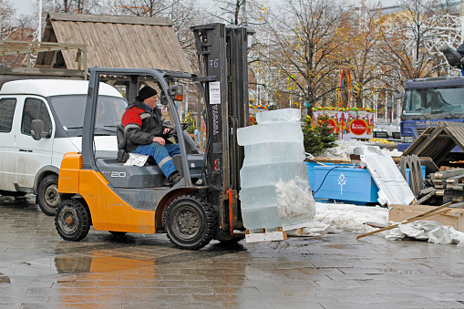 Moscow, Russia - February 27, 2017: A forklift worker makes transportation of ice blocks to storage sites