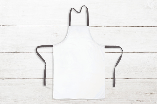 Blank white apron on white wooden background