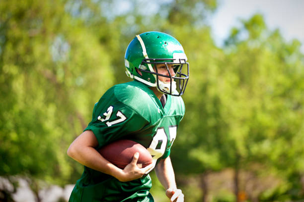 High School  or University American Football Player Playing in Field A high school or university American football player playing in an outdoor football field. He is carrying a football running. bernalillo county stock pictures, royalty-free photos & images