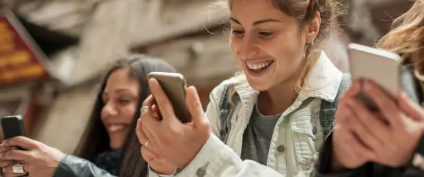 Photo of Happy girl friends watching internet social media in cell phone