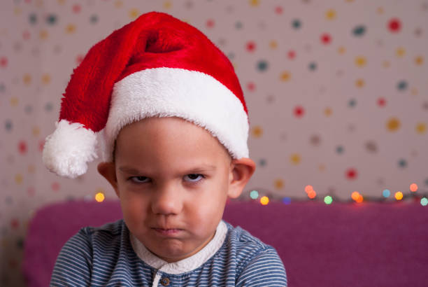 angry boy in a santa hat stock photo