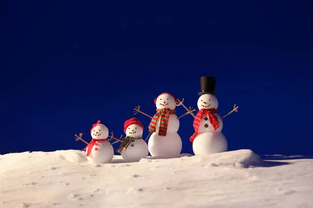 A happy winter snowman couple wearing a festive Christmas themed scarf with a sky background.