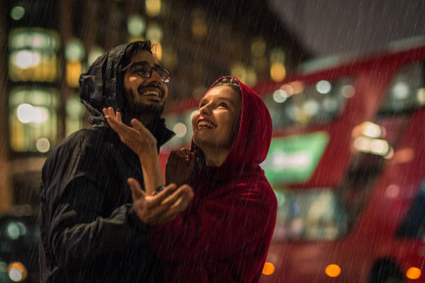 giovane coppia che si diverte sotto la pioggia - london in the rain foto e immagini stock