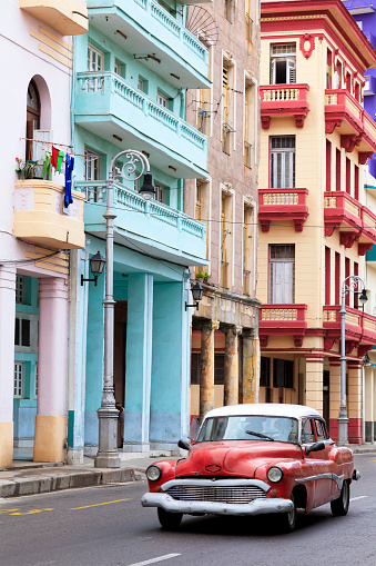 Vintage American cars speeding in front of dilapidated buildings in traditional colonial style, Havana, Cuba, 50 megapixel image