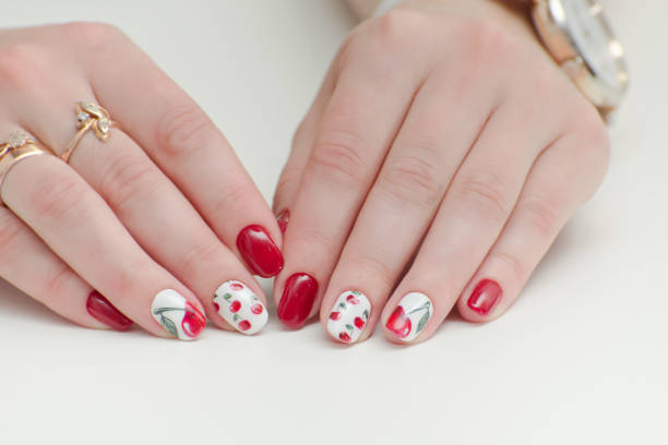 istock Female hands with manicure, red nail polish, drawing with cherries. White background. 867563124