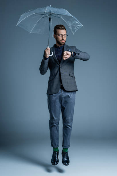 istock Man with umbrella looking at watch 867563490