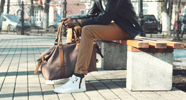 Fashion man with bag sits on a bench in the city close-up stock photo