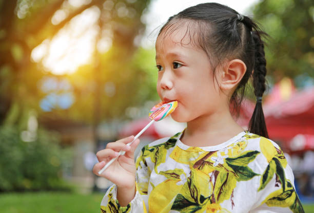 istock Little asian girl eating candy lollipop. 867654314