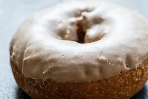 Close up macro shot of a maple, butterscotch or caramel donut on a dark surface