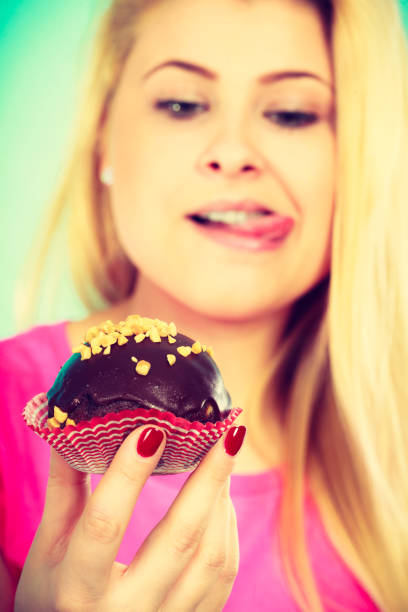 istock Cute blonde woman about to eat cupcake 867664462