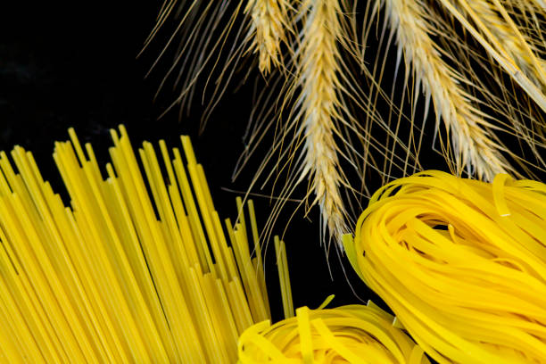 istock Macaroni and spikelets of wheat on a black background 867667882