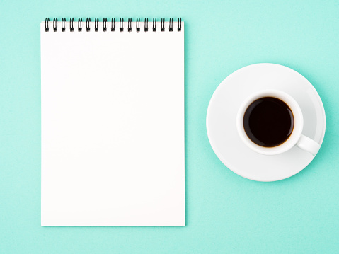 Bloc de notas abre con página en blanco en blanco para escribir la idea o la tarea lista, una taza de café sobre fondo azul brillante photo