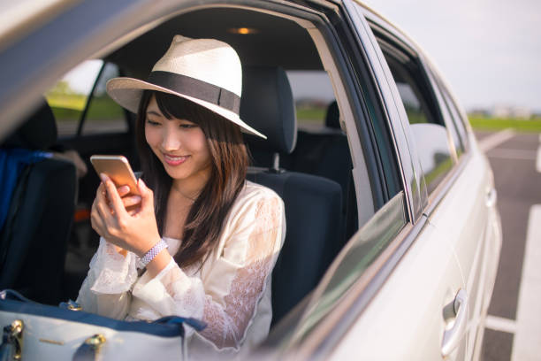 Young woman sitting on passenger seat and watching screen on smart phone stock photo