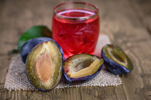 traditional homemade plum liqueur and berries plums on a rustic table. - plum fruit organic food and drink imagens e fotografias de stock