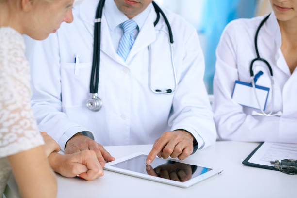 istock Doctor and  patient talking while sitting at the desk in office. Physician pointing into touch pad computer or tablet. Medicine and health care concept 867680340